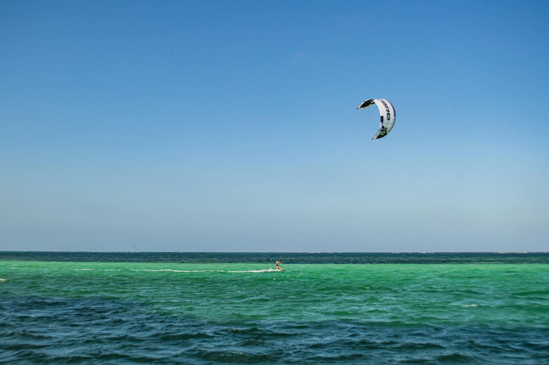 Kite surfer gliding over turquoise waters.