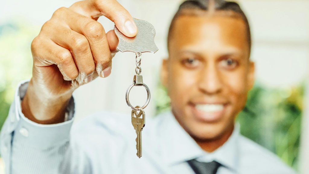 A man showing his house key after listing his property online in Kenya.